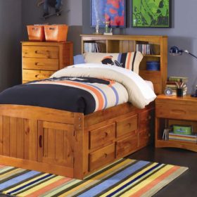 Toàn bộ nội thất phòng ngủ làm từ gỗ thông đồng màu với giường lớn tích hợp ngăn tủ để đồ và một số đồ dùng cơ bản khác